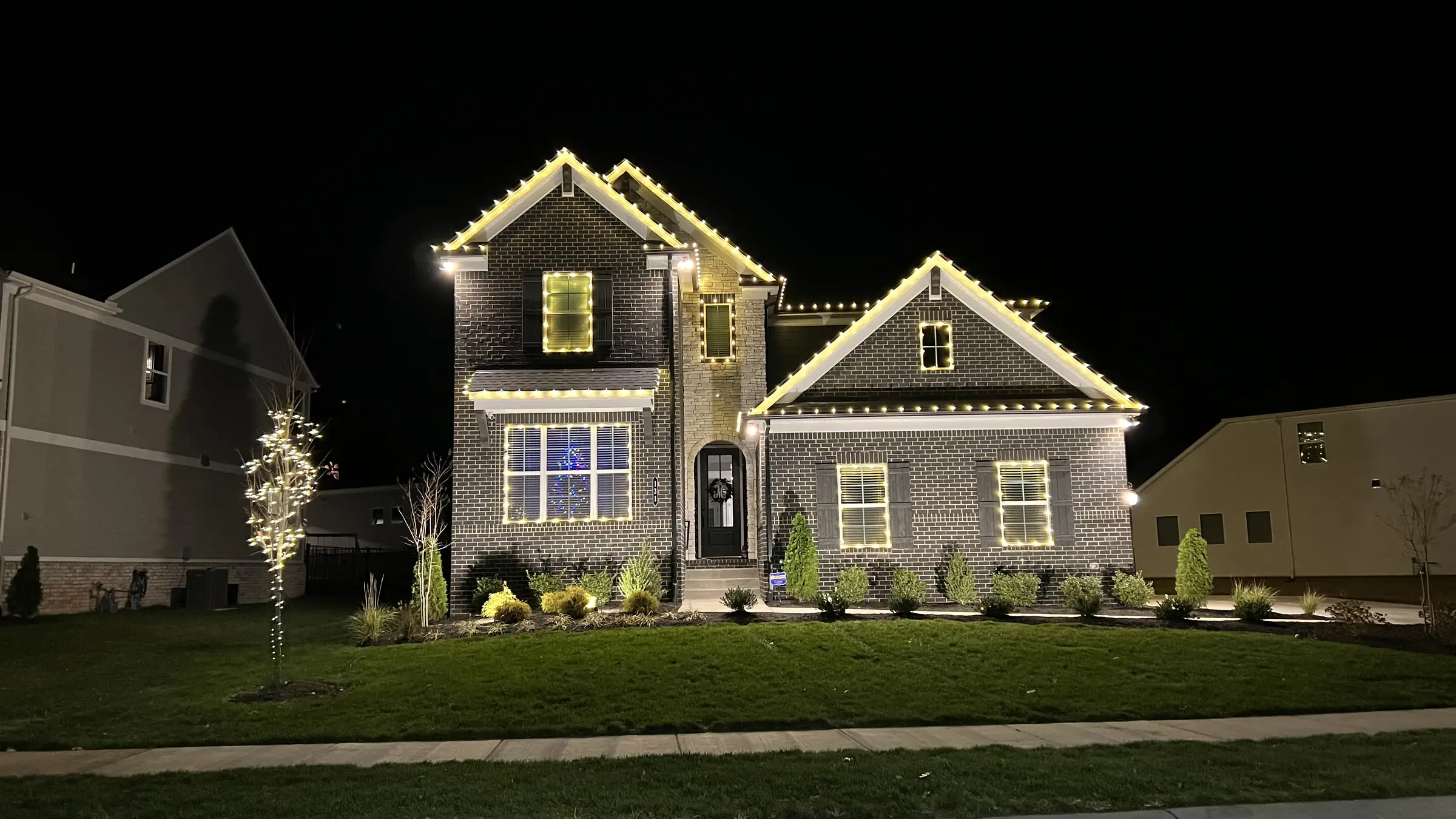 Permanent roofline lighting running warm white on a home in White House, Tennessee