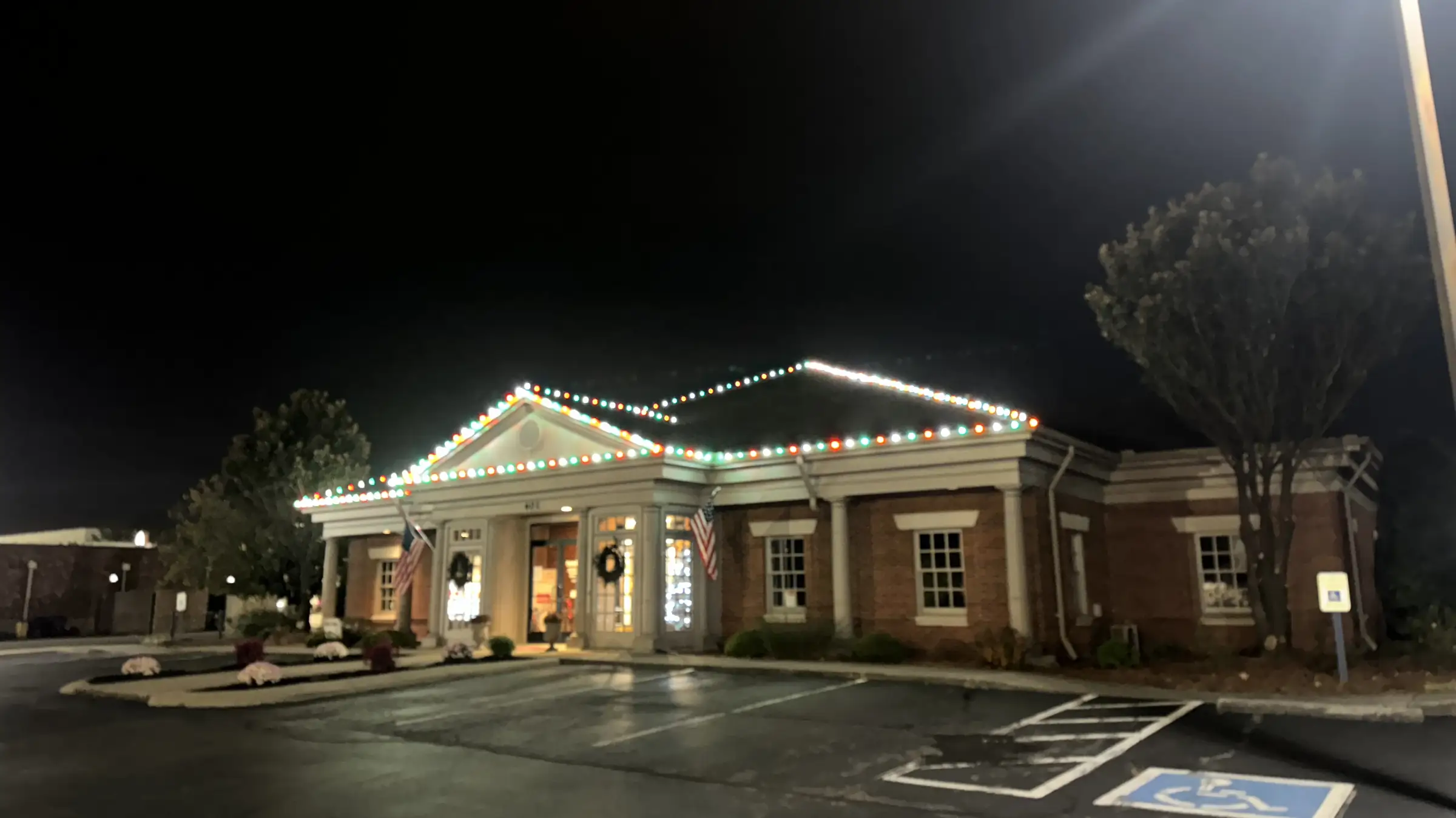 A single story commercial building in Springfield, Tennessee with red, green and white lights along the full roofline and lit wreaths at the entrance