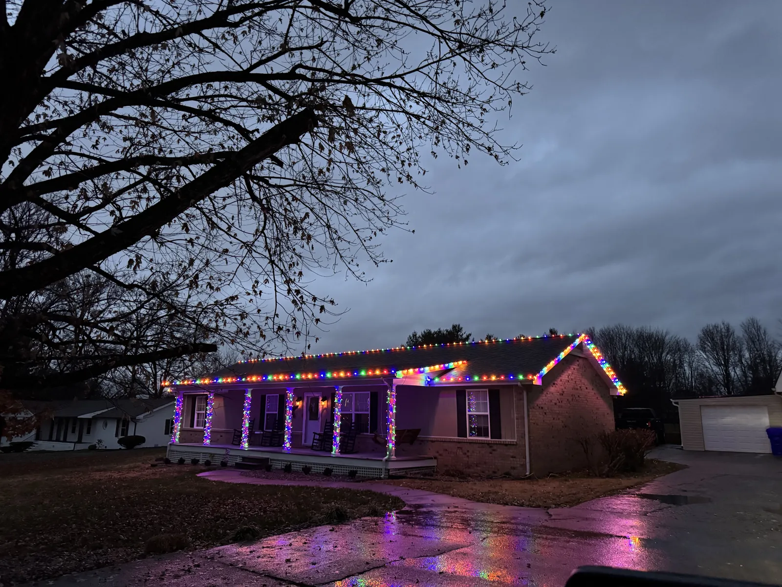 A brick ranch house in White House, Tennessee in multicolor lights, reflected on a wet driveway
