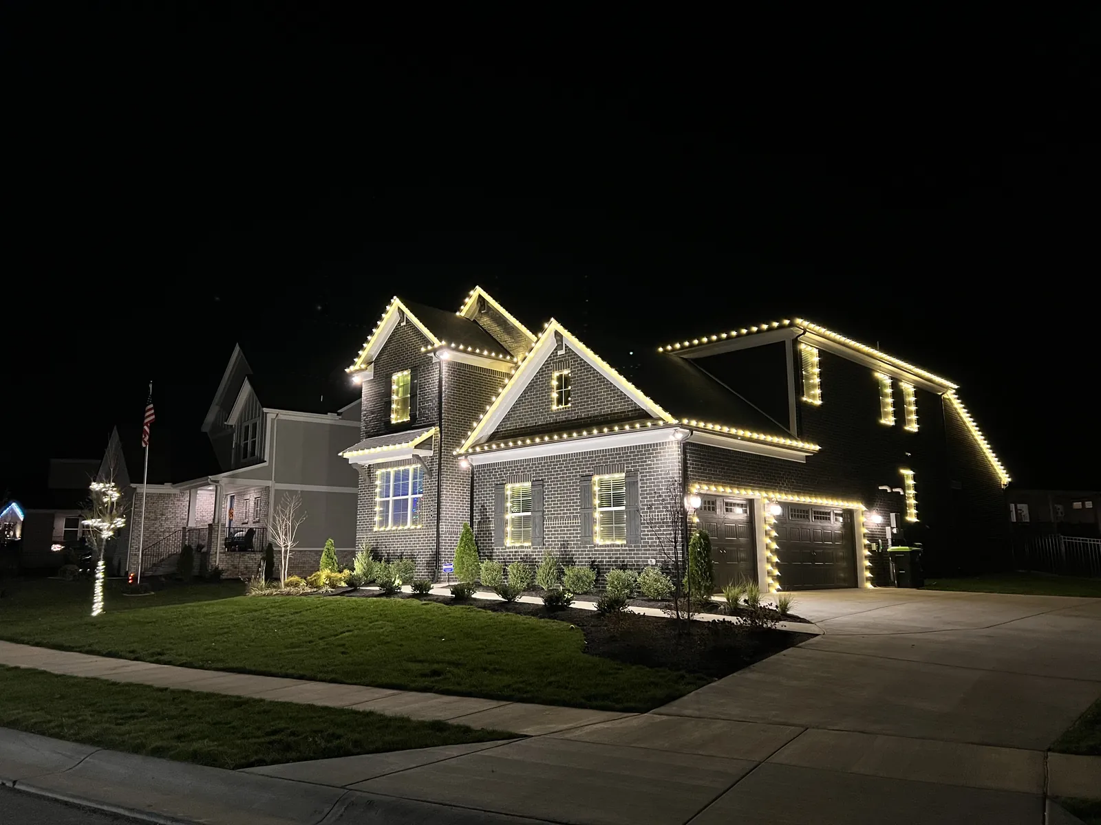 A two story home in White House, Tennessee with warm white lights along every roofline and gable