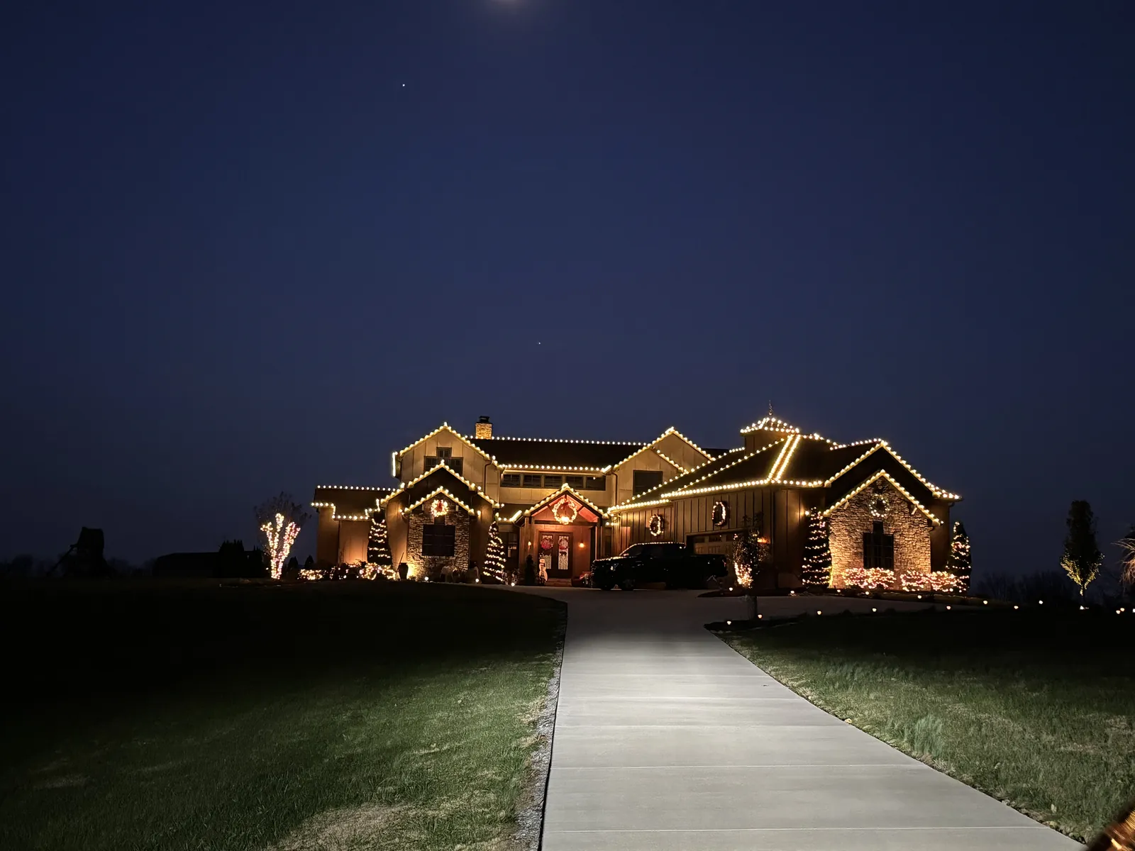 A home lit across the whole front after dark, with a lit path leading up to the door