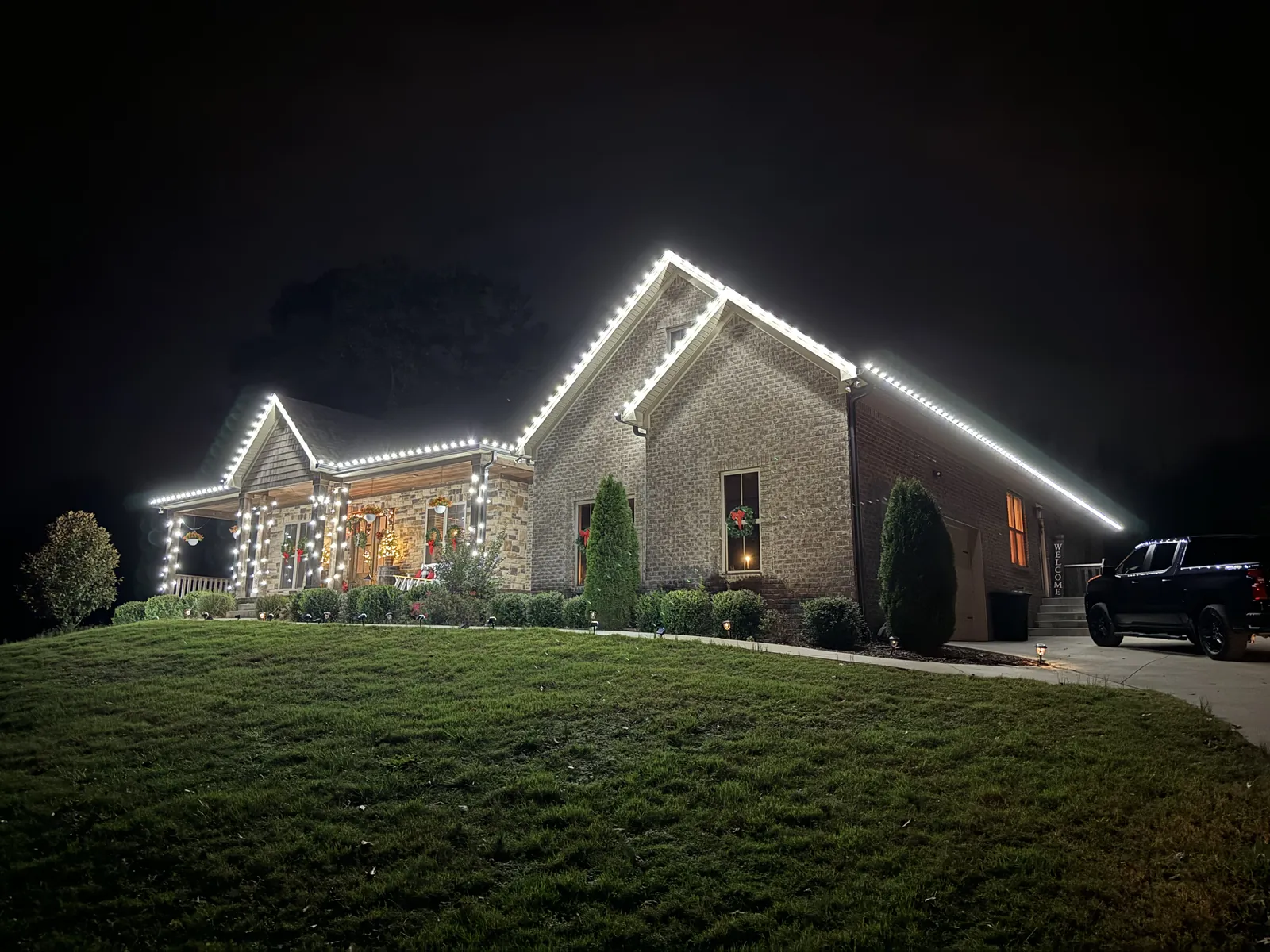 A single story home with warm white lights running the full length of the roofline and gable