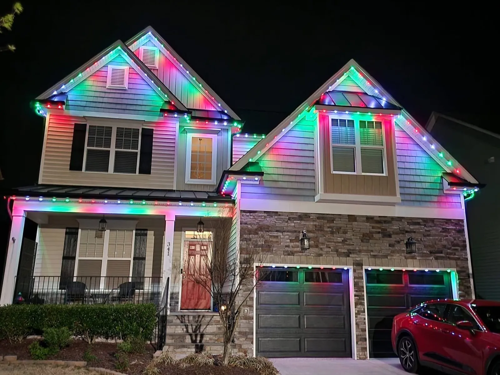 A two story home running permanent color-changing lights in pink and green along the rooflines and porch