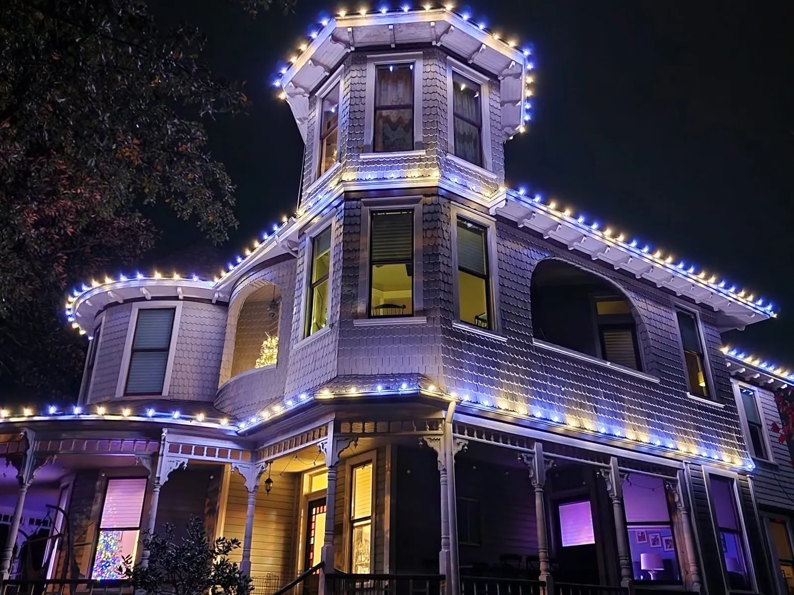 The same Victorian house, this time lit blue and white
