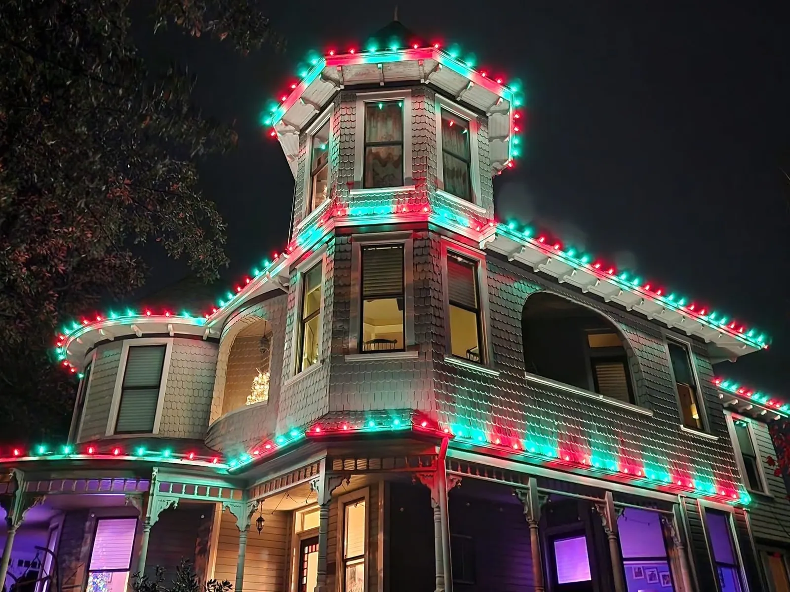 A Victorian house outlined in red and green along its turret, rooflines and porch rails